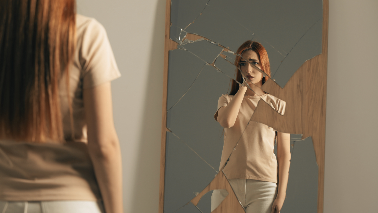 Silhouette réfléchissante dans un miroir brisé, symbolisant l'impact des manipulateurs sur la confiance en soi.