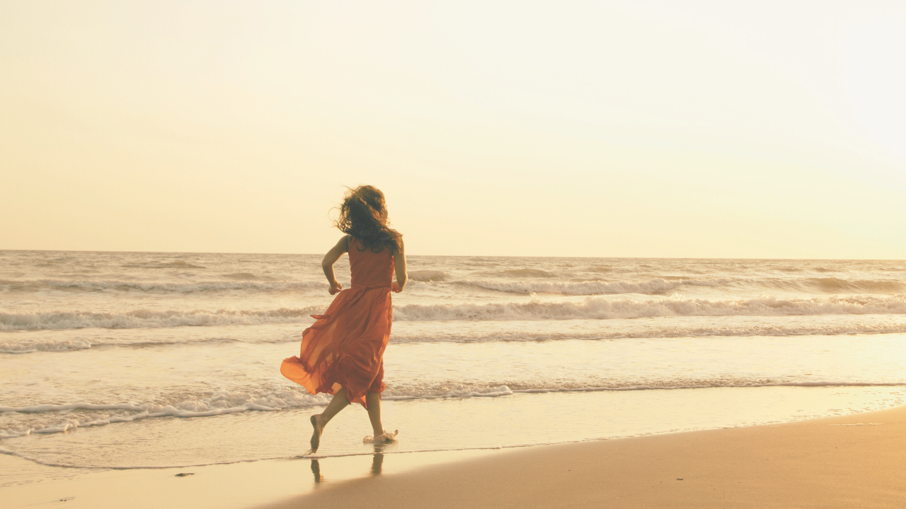 Une femme courant sur une plage, symbolisant les choix et décisions pour se choisir en 2025, avec un coucher de soleil apaisant en arrière-plan